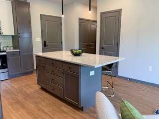 Large kitchen island with abundant storage and bar stools and pendant lights in the Bliss floor plan at Haven at Uptown in Lincoln.