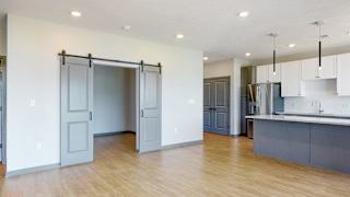 View of sliding barn doors leading into the office area from the living-dining space in the Melody floor plan at Haven at Uptown in Lincoln, NE