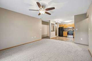 Open-concept living and dining area with a ceiling fan, carpeted flooring, and an updated kitchen visible beyond.