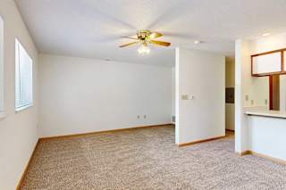 Alternate view of living room with light walls and ceiling fan