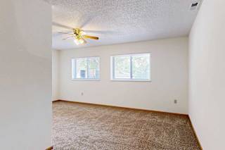 Carpeted sleeping area with ceiling fan and two windows