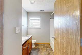 A bathroom with a toilet, sink, and window.