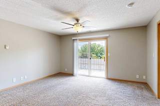 a bright carpeted living room with large sliding glass door