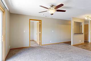 a living room with ceiling fan, sliding glass door, and door to the den space