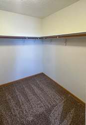 A walk-in closet with built in shelving and hanging space.