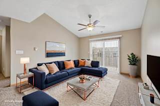 Virtually staged living room with a sectional sofa, coffee table, ceiling fan, large window, and neutral apartment finishes.