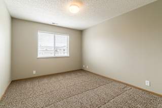 a bedroom with a carpeted floor and a window with blinds