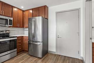 A modern kitchen with a stainless steel refrigerator and wooden cabinets.