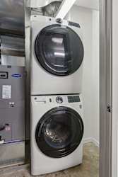 A white front load washing machine is stacked on top of another in a room.