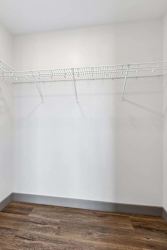Empty closet with a white wall and a shelf.