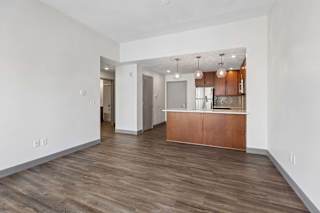A spacious room with wooden flooring and a kitchen area.