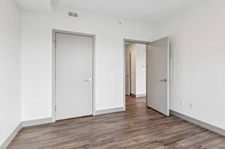A bedroom with hardwood-style flooring and a walk-in closet.