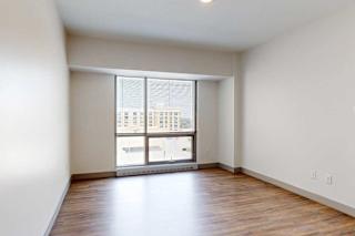 A bedroom with hardwood-style flooring and a floor-to-ceiling window.
