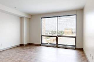 A living room with hardwood-style flooring and a floor-to-ceiling window.