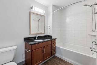 A bathroom with a white tub, sink, and a mirror.