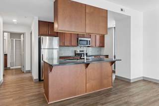 A kitchen with a refrigerator, microwave, and stove top oven.