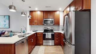 Spacious kitchen with peninsula and quartz or granite counter top and tile back splash in a 1 bedroom floor plan at Midtown Crossing Apartments Omaha