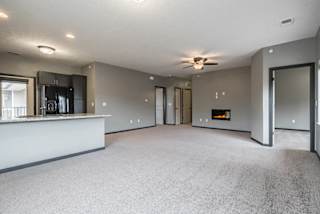 Living room with electric fireplace and ceiling fan at The Villas of Omaha at Butler Ridge in Omaha Nebraska