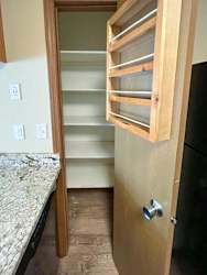 a kitchen with a pantry with additional storage shelves hanging on the door