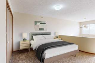 A bedroom with a large bed and a nightstand with a lamp.