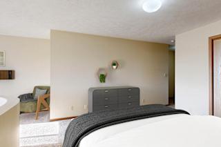 A bedroom with a bed, nightstand, and chair.