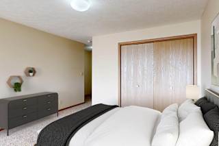 A bedroom with a bed, dresser, and closet with bifold doors.