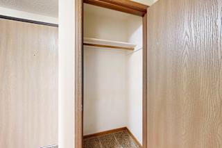 A coat closet with a built-in overhead shelf and hanging bar.