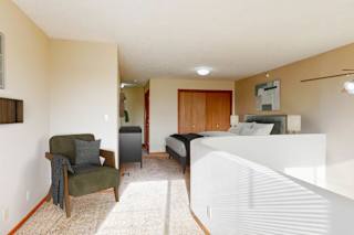 A bedroom with a bed, chair, and a cabinet.