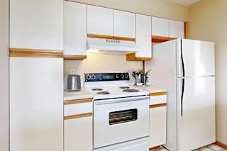 A white kitchen with a stove, oven, and refrigerator.