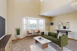 A virtually staged apartment living room with a green couch and a coffee table.