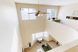 View of a living room looking down from a lofted bedroom