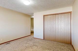 A loft bedroom with a carpeted floor and double-door closet.