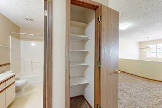 A linen closet with built-in shelves, next to an open door to the bathroom.