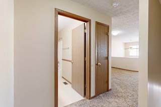 A hallway at the top of the stairs with a door to the loft bathroom and a linen closet.