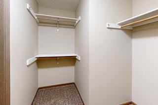 A spacious walk-in closet with three built-in shelves and hanging space.