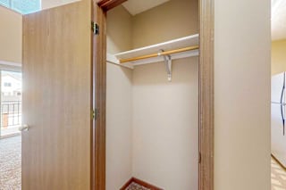A coat closet with a built-in shelf and hanging rod.