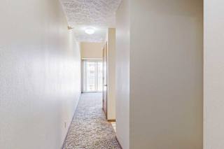 A hallway with an alcove to the hallway bathroom, access to the kitchen, and the living room at the end.