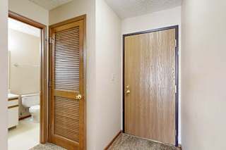 A front door next to an open door to a hallway bathroom.