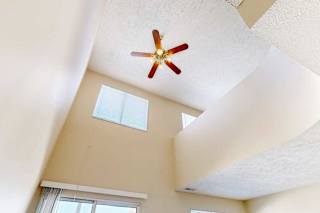 A view of the loft area above from the living room, with two windows and a ceiling fan.