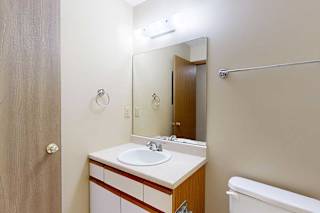 A bathroom with a vanity sink, mirror, and towel rack.