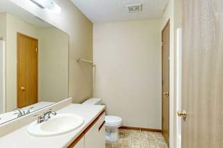A bathroom with white and oak cabinetry, a wide vanity sink, and a large mirror with overhead lighting.