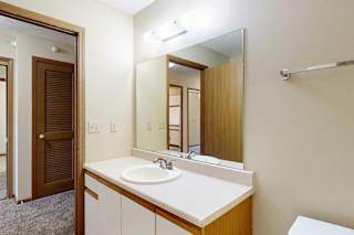 A bathroom with white and oak cabinetry, a wide vanity sink, and a large mirror with overhead lighting.
