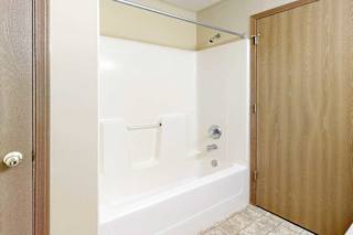 A bathroom with a white tub shower and chrome finishes.