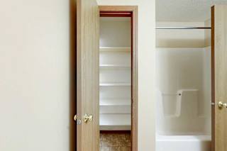A bathroom with a linen closet, with several built-in shelves.
