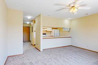 A living area with a ceiling fan and a counter with a passthrough window to the kitchen.
