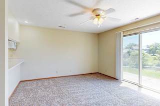 A living area with a ceiling fan and a sliding glass door to a patio, providing plenty of natural light.