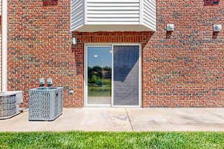 A red brick building with a wide patio space next to a green lawn.
