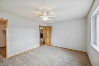 A room with a ceiling fan and carpeted floor.