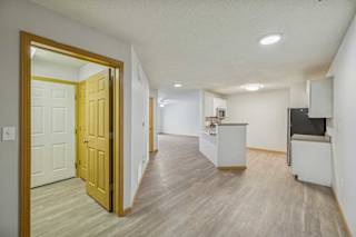 A room with a wooden floor and a white wall with a door.