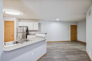 A kitchen with a refrigerator, sink, and cabinets.